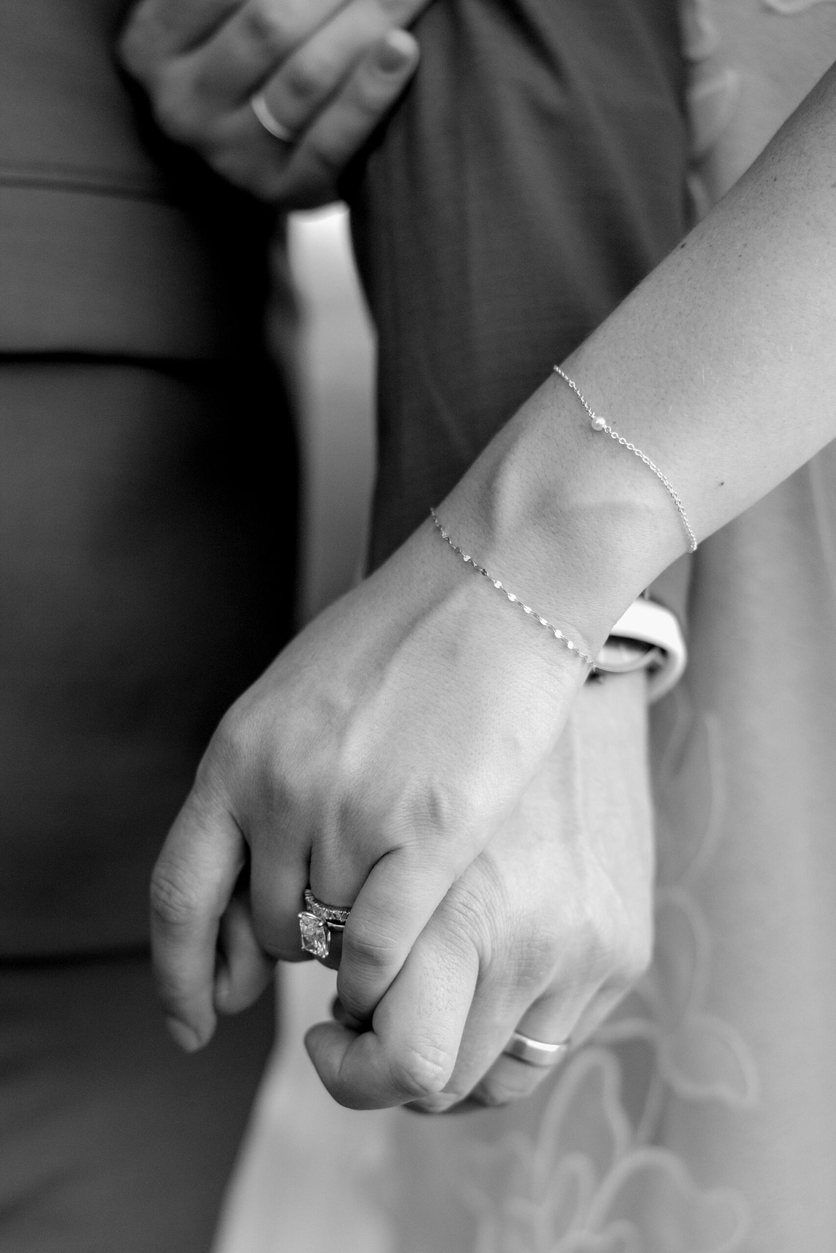 Close up of bride and groom's hands in black and white